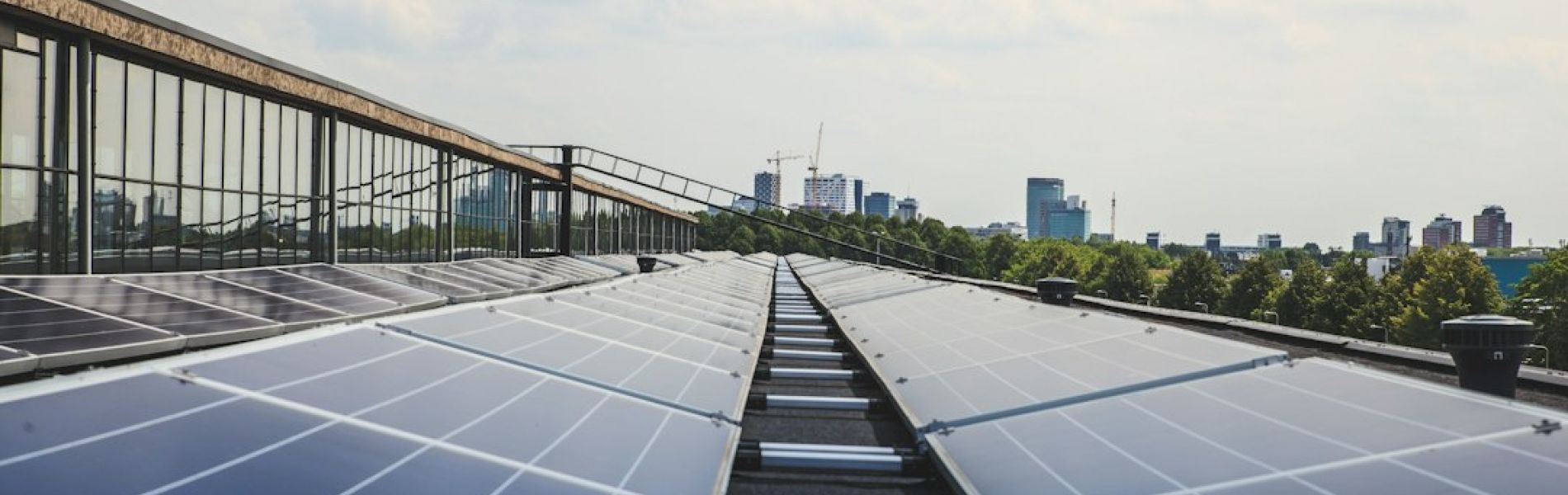 Instalación de placas solares en azotea de edificio con vista a la ciudad y rascacielos al fondo
