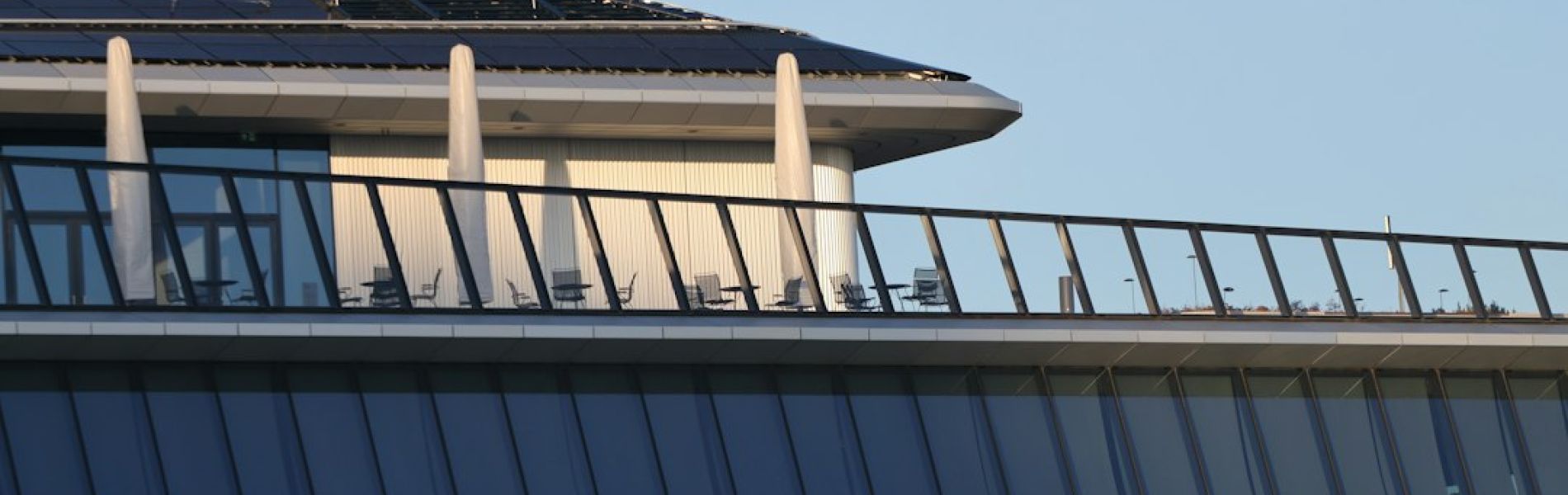 Edificio moderno con paneles solares en la azotea y grandes ventanales de vidrio en la fachada