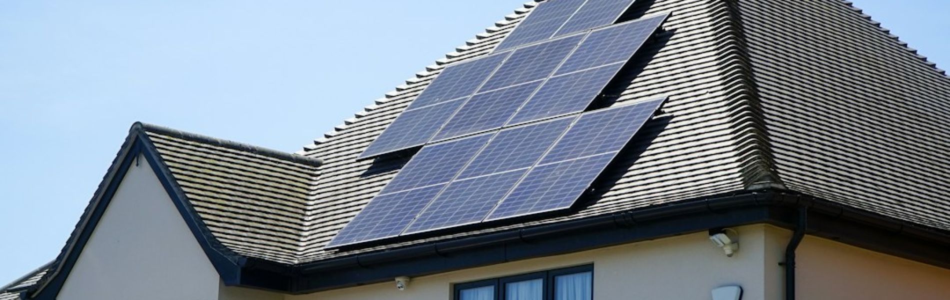 Casa moderna con placas solares instaladas en tejado gris con ventanas azules