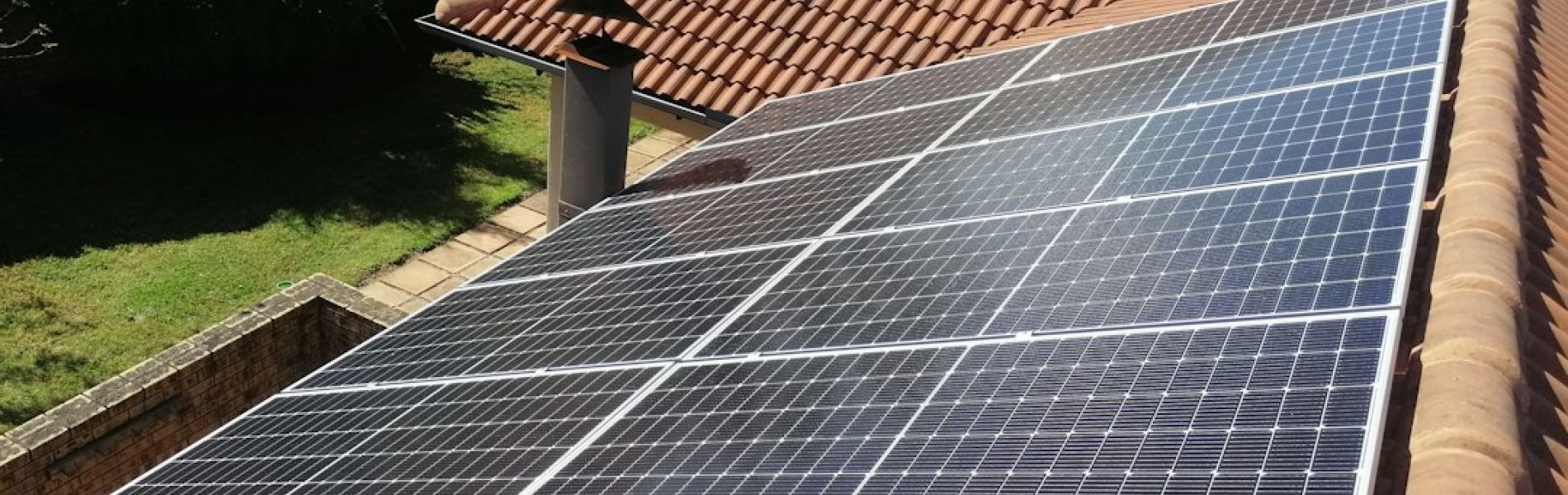 Paneles solares instalados en tejado de vivienda con tejas terracota, mostrando la colocación en superficie plana del techo