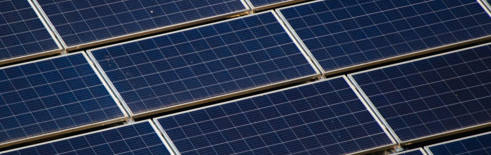 Detalle de múltiples placas solares azul oscuro con marco metálico conectadas en instalación de energía renovable