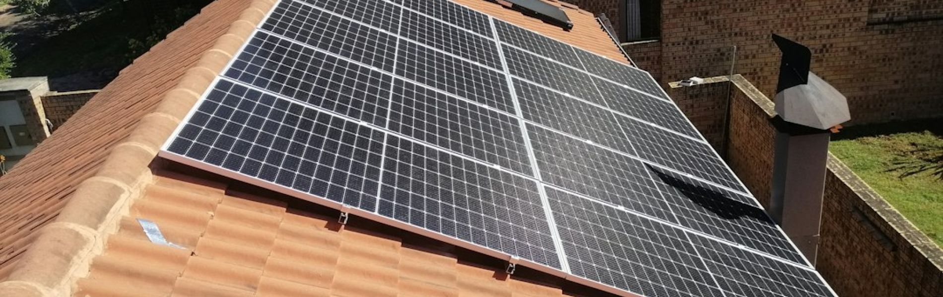 Instalación de placas solares en tejado de tejas de barro rojo de vivienda unifamiliar con ladrillo visto